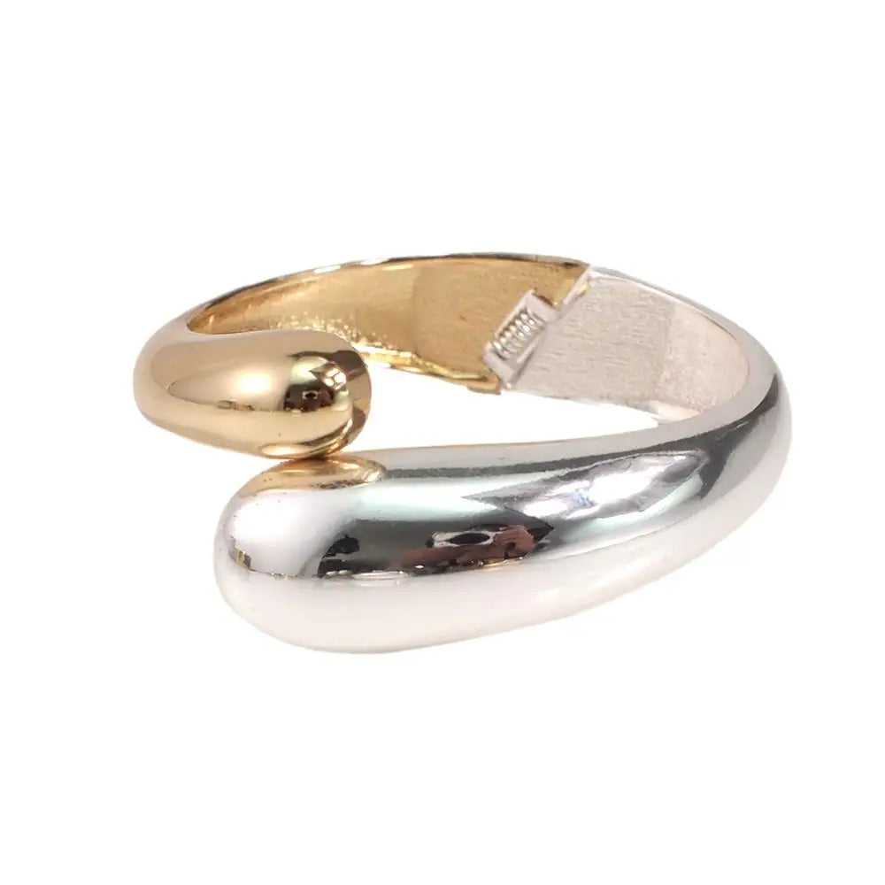 Elegant cuff bracelet featuring silver and gold plating with a glossy sculpted surface.